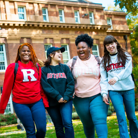 Smiling students holding Rutgers excellence shirts in The Yard